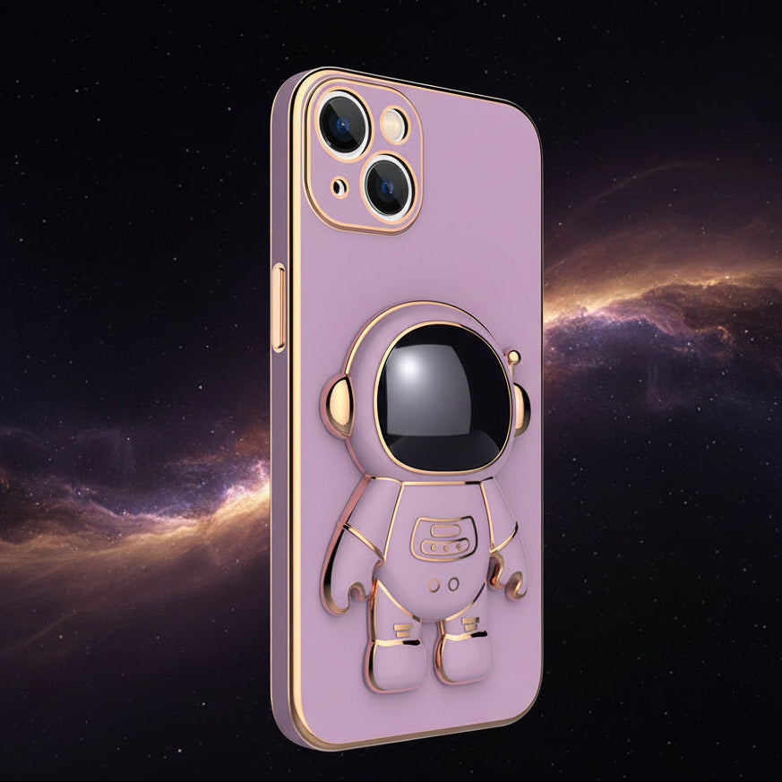 A light purple phone case with a 3D astronaut design, featuring gold metallic accents and a black visor, shown against a dark space background with nebulae.
